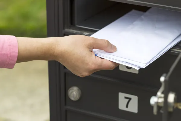 A photo of a girl putting unmarked mail into a mailbox