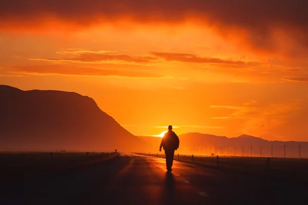 This is a photo of a gentleman walking on the highway at sunset
